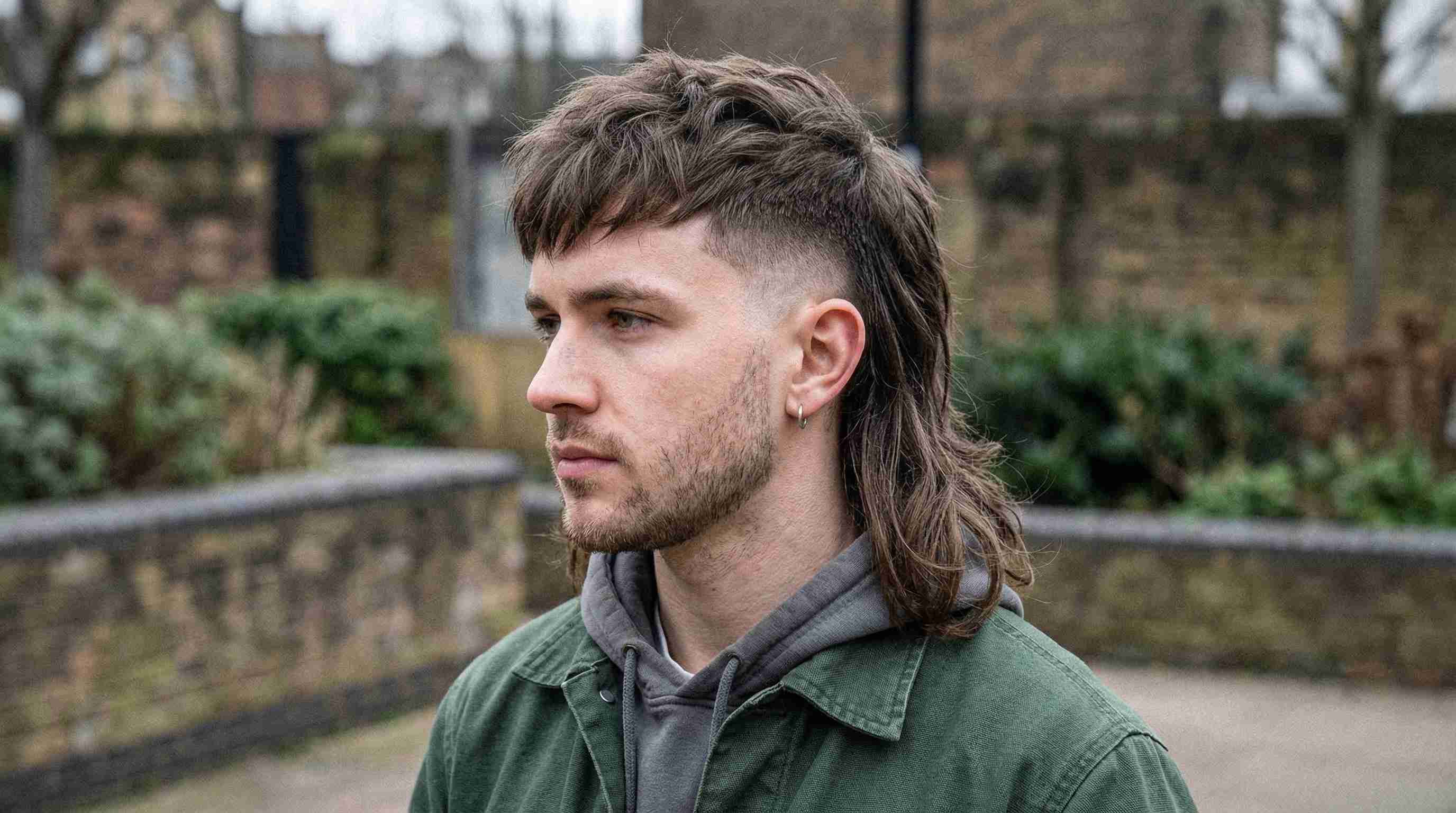 A man with a mohawk and skin burst fade mullet sits in a barber chair, ready for a haircut.